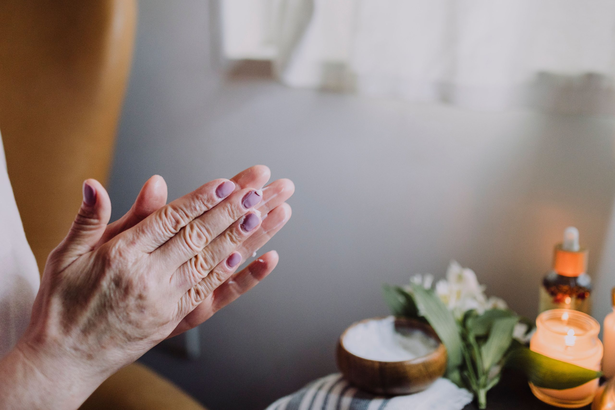 A pair of hands rubbing together with a relaxing background of oils, salts and candle